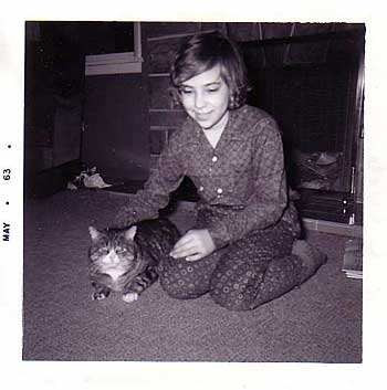 Black and white photo of a girl kneeling on the floor with a black and white tabby cat sitting beside her.