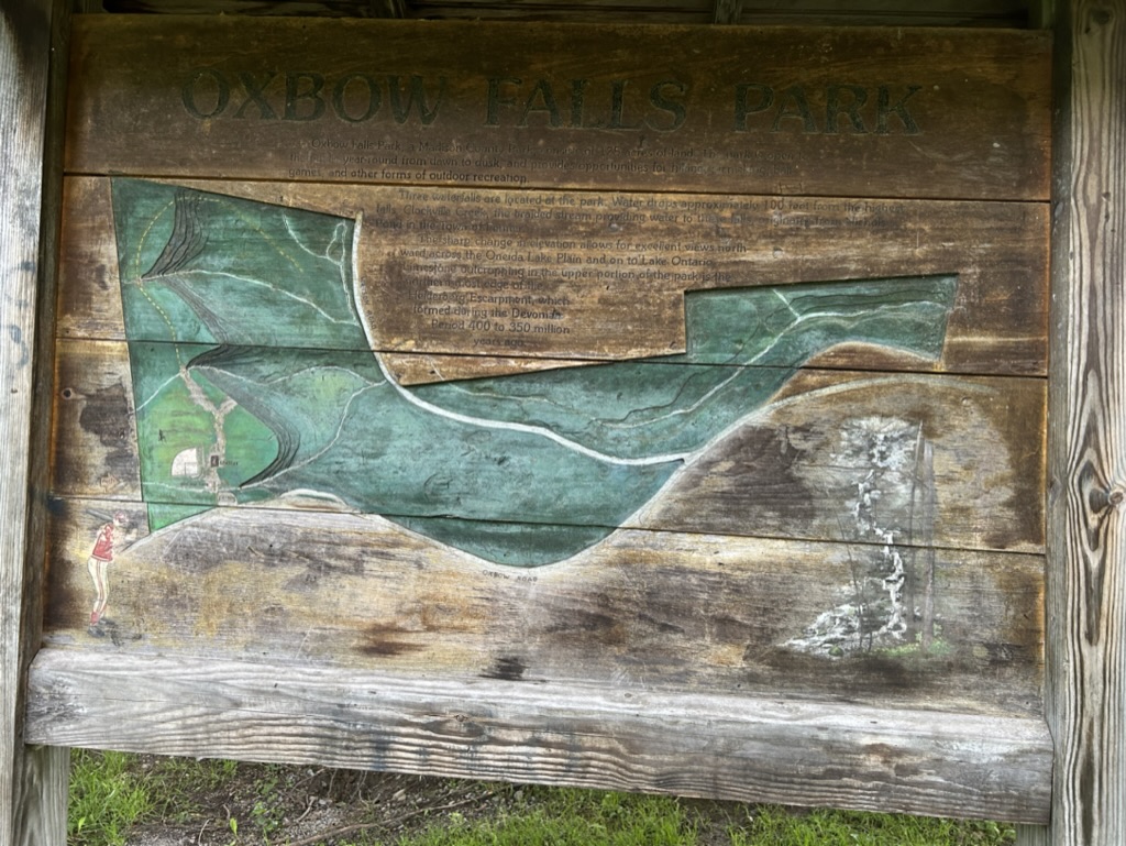 A faded wooden sign with a map of Oxbow Falls Park