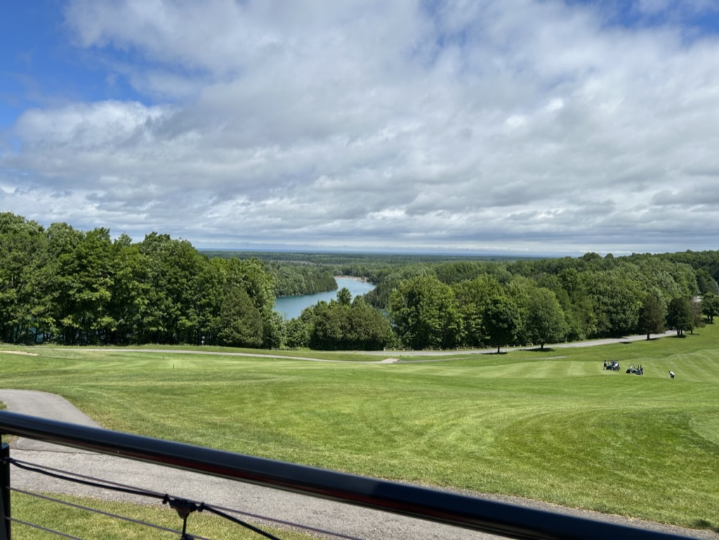 View of a golf course with trees in the distance and fluffy white clouds in the sky