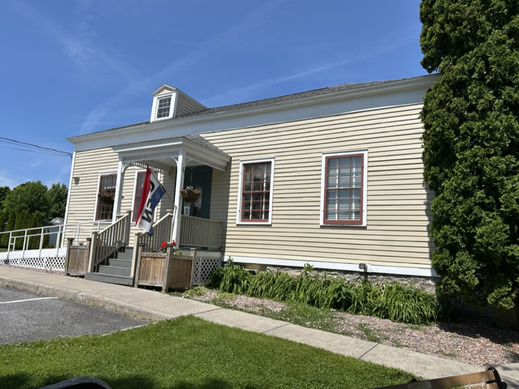 Sackets Harbor Visitor Center, a pale beige building with a small covered porch entrance