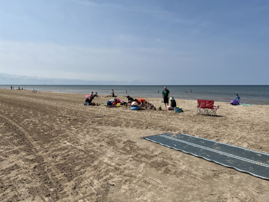 People seated on the beach make sand castles