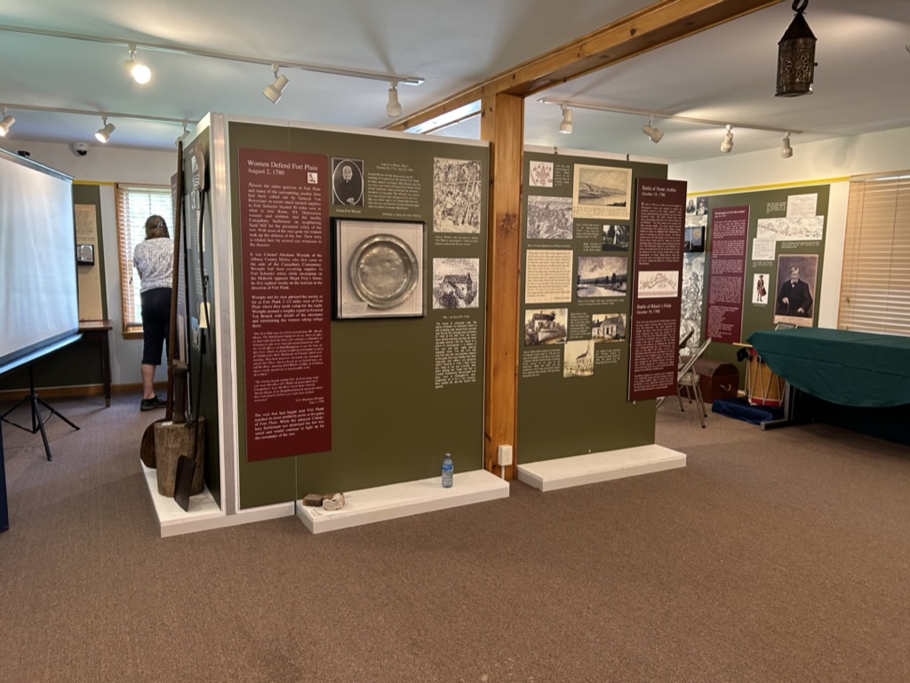 Inside the Fort Plain Museum, an interior dividing wall is covered in photographs and placards with descriptions of historical items