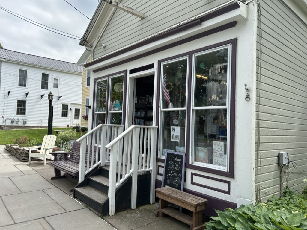 A white storefront with steps leading up to the door, and many windows full of bric-a-brac