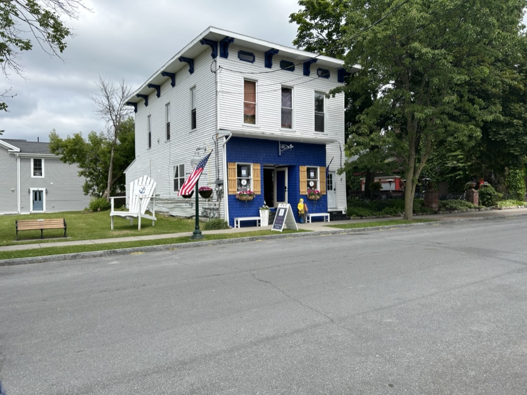 A square, two-story building with a gift shop on the ground floor. The building is painted white, except for a navy blue storefront