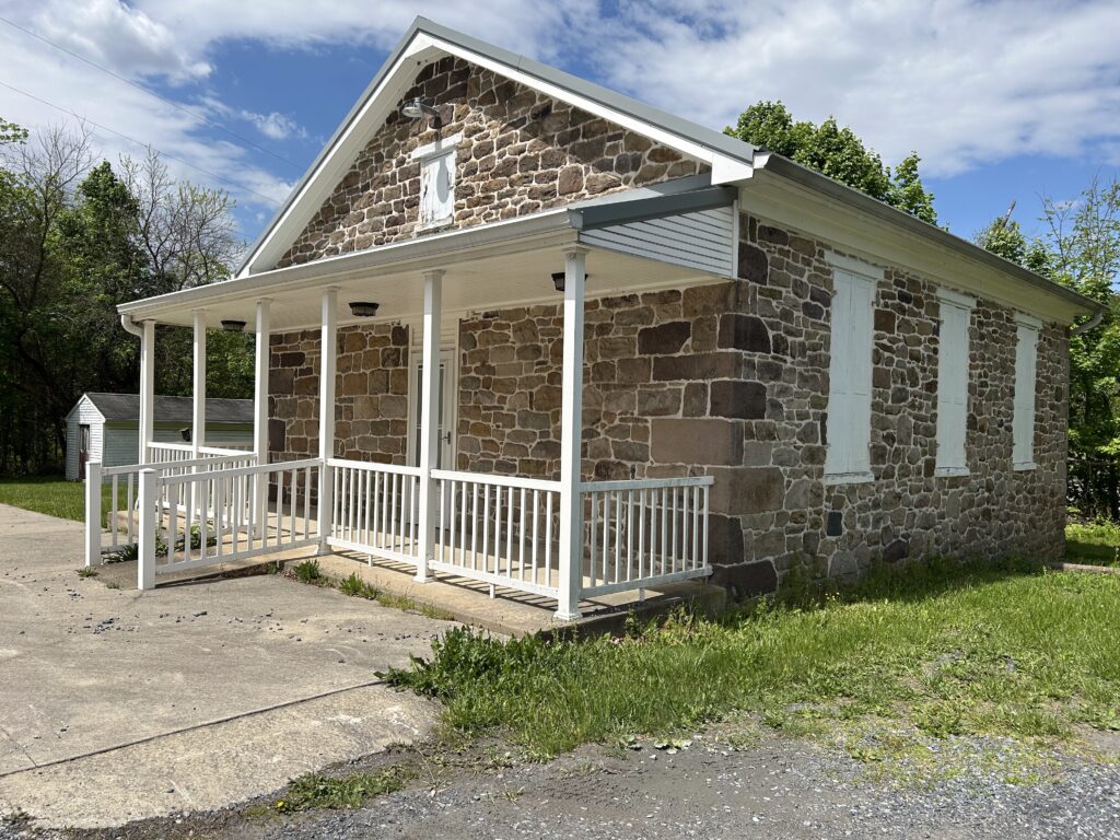 An old stone schoolhouse with a white patio in front