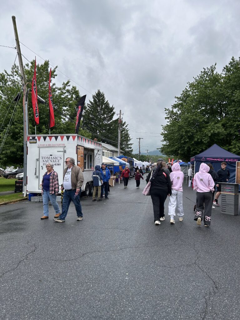 Food trucks and craft booths line the street at a street fair