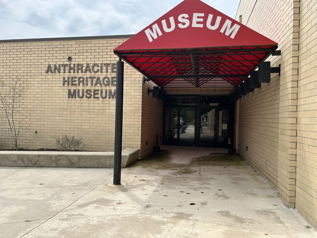 The entrance to the Anthracite Heritage Museum, a tan brick building with entryway covered by a red canopy